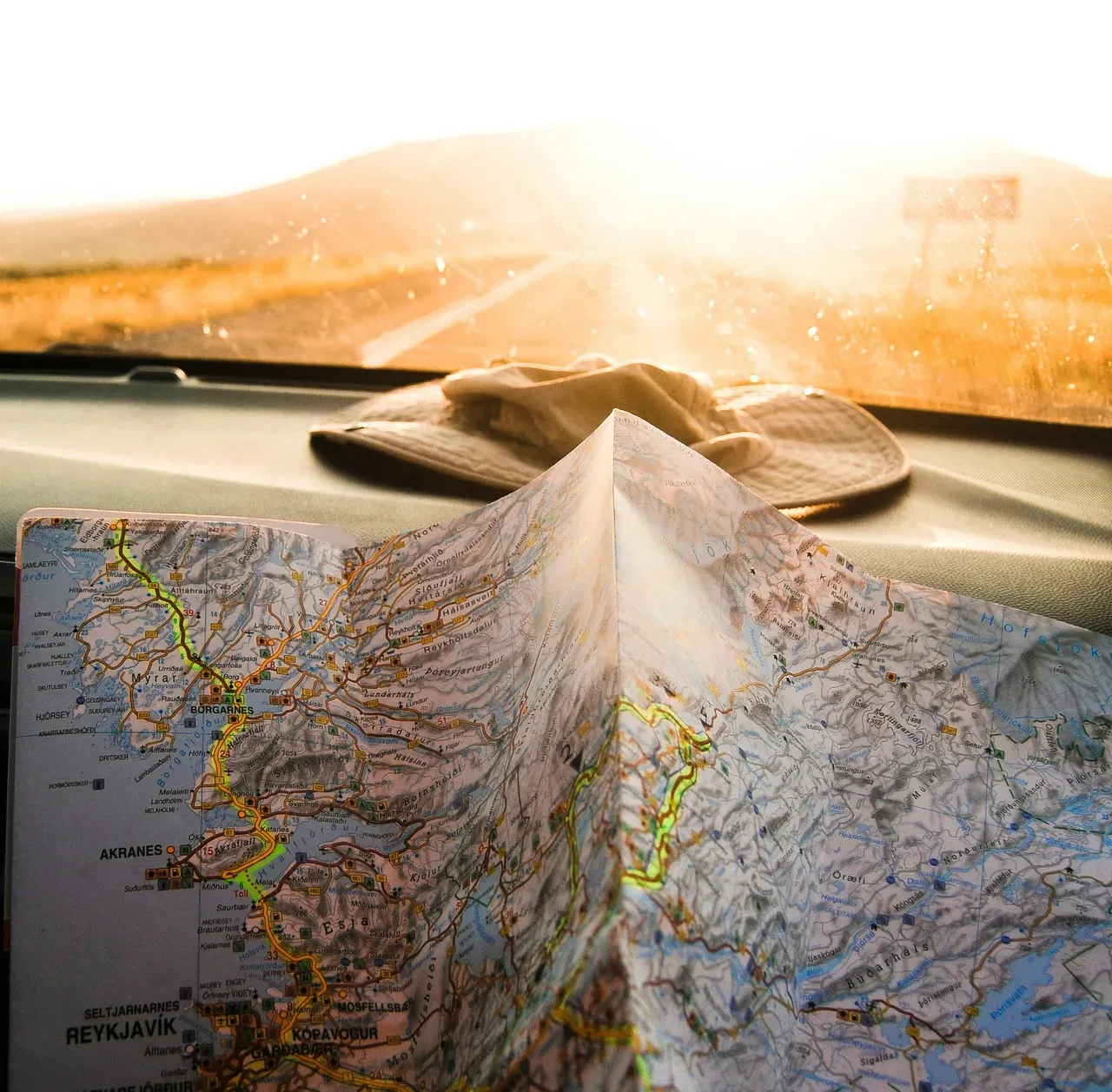 Paper road map and travel hat on a car dashboard during a European road trip